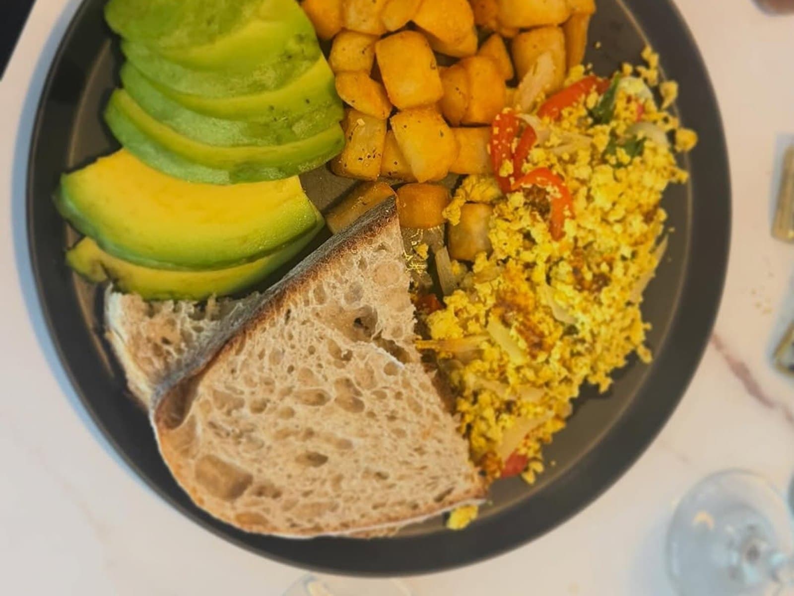 Desayuno de origen vegetal con tofu, aguacate, papas y pan en Café 413