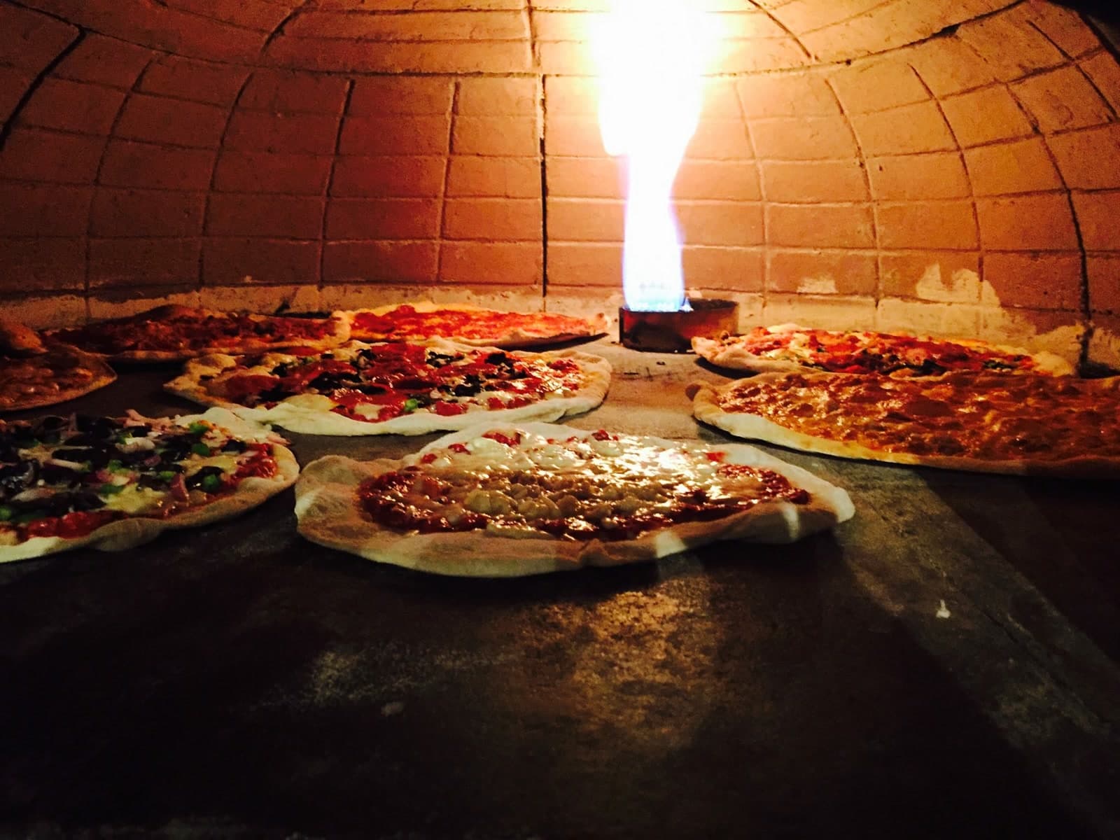 Pizzas artesanales cocinándose en el horno de ladrillo de Mi Familias