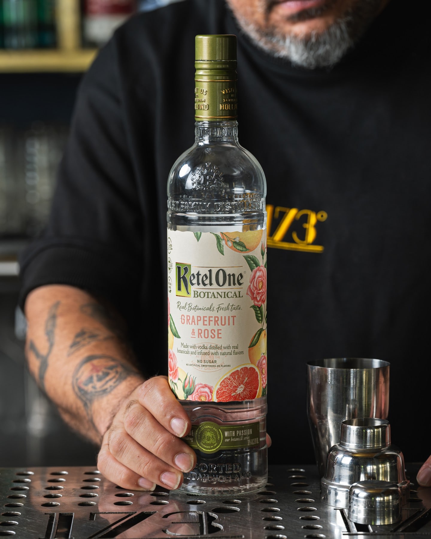 Bartender de 173 grados presentando una botella junto a la estación de servicio