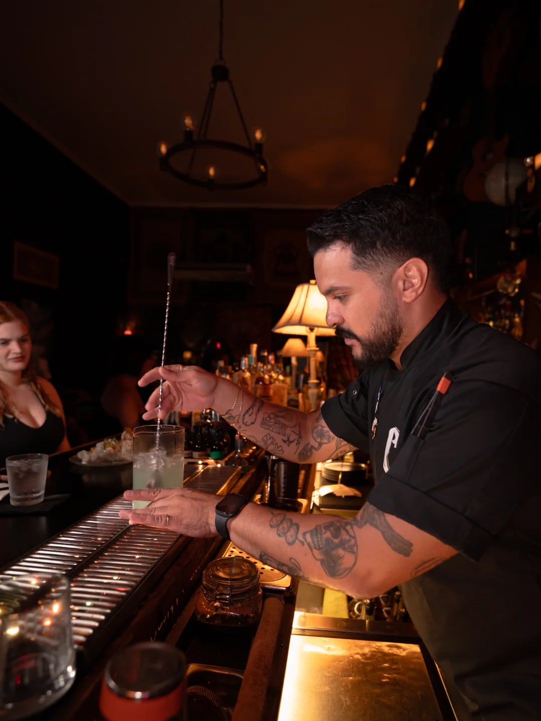 Bartender de El Cubujón trabajando frente a la colección de botellas