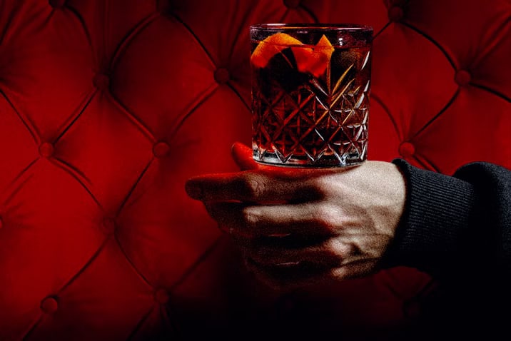 Coctel oscuro servido frente al tapizado rojo de Furtivo